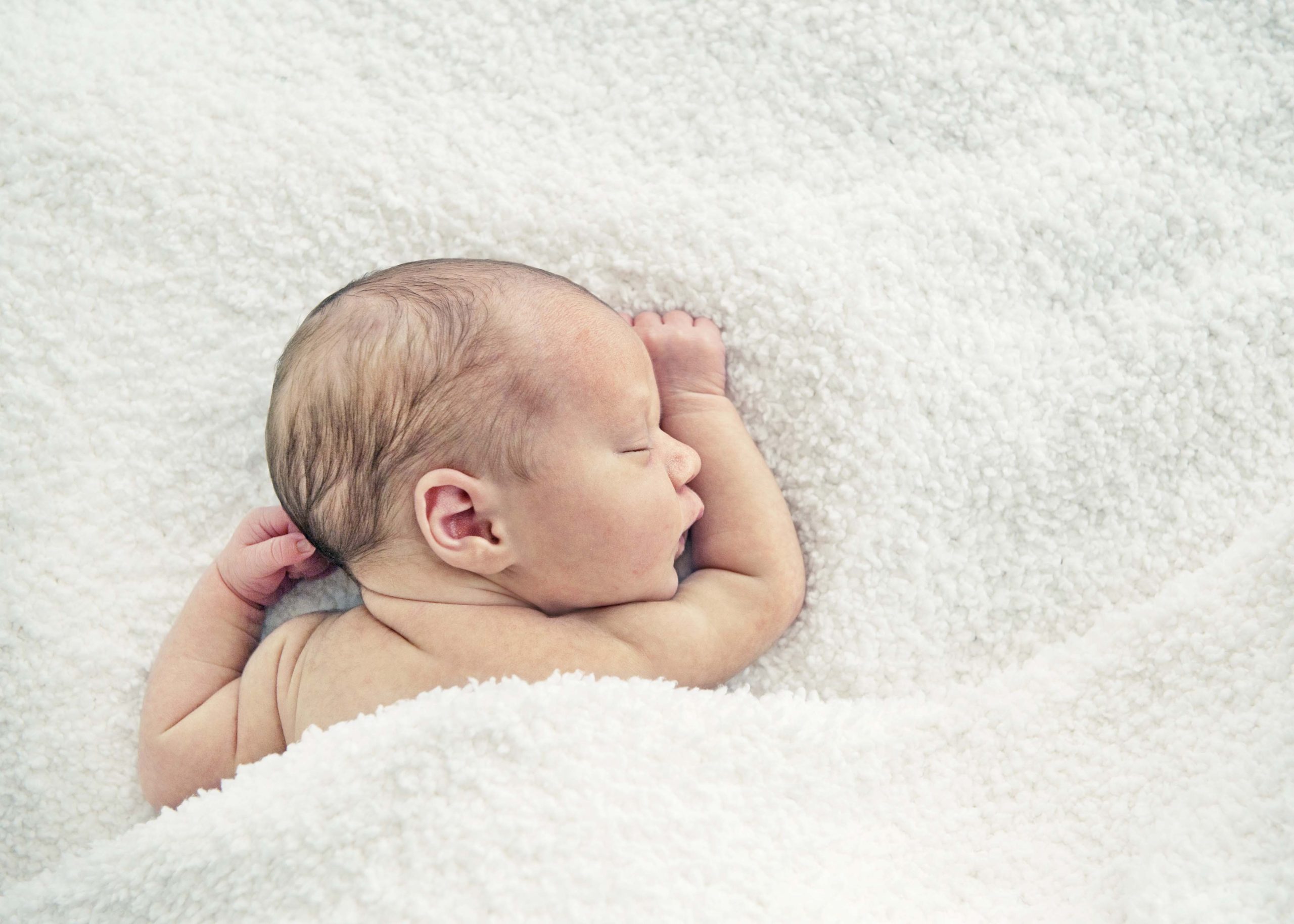 Newborn baby sleeping under blanket